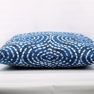 May include: A blue and white patterned cushion with a geometric design. The cushion is made of a soft, textured fabric.