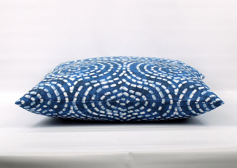 May include: A blue and white patterned cushion with a geometric design. The cushion is made of a soft, textured fabric.