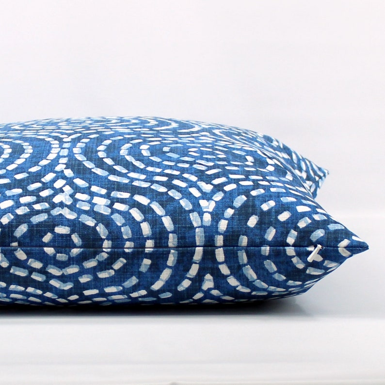 May include: A blue and white patterned cushion with a geometric design. The cushion is made of a soft, textured fabric.