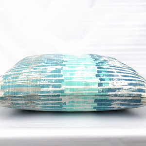 Puede incluir: Una almohada de tiro a rayas azules y grises con un patr&oacute;n de pinceladas. La almohada est&aacute; hecha de una tela suave y c&oacute;moda y es perfecta para agregar un toque de estilo a cualquier habitaci&oacute;n.