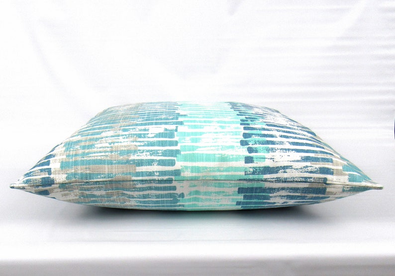 Puede incluir: Una almohada de tiro a rayas azules y grises con un patr&oacute;n de pinceladas. La almohada est&aacute; hecha de una tela suave y c&oacute;moda y es perfecta para agregar un toque de estilo a cualquier habitaci&oacute;n.