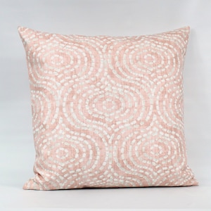 Puede incluir: Una almohada rosa con un patr&oacute;n geom&eacute;trico blanco de c&iacute;rculos. La almohada est&aacute; hecha de una tela suave y texturizada.