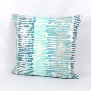 Puede incluir: Una almohada decorativa con un patr&oacute;n de rayas azules y blancas. Las rayas son de color azul claro, azul oscuro y blanco. La almohada est&aacute; hecha de una tela suave y texturizada.