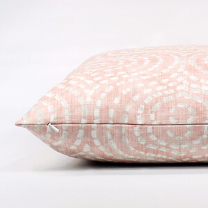 Puede incluir: Una almohada rosa con un patr&oacute;n de remolino blanco. La almohada tiene una cremallera.