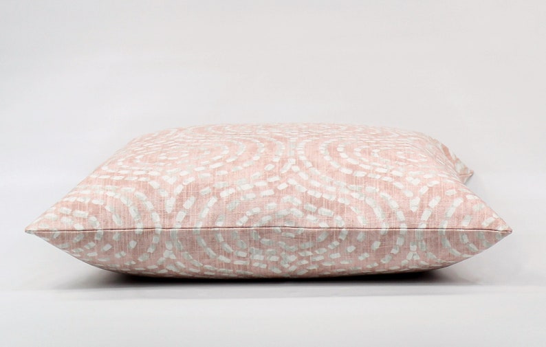 Puede incluir: Un coj&iacute;n de tiro rosa y blanco con un dise&ntilde;o de remolino sutil.