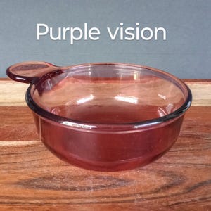 Pode incluir: Uma tigela de vidro transparente tingida de roxo com uma al&ccedil;a. A tigela tem formato arredondado e uma borda roxa escura. O texto "Purple vision" est&aacute; acima da tigela. A tigela est&aacute; sobre uma superf&iacute;cie de madeira.