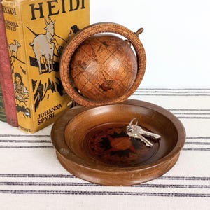 May include: A wooden decorative bowl with keys inside, a small globe, and several vintage books. The globe is set in a wooden frame. The books are in various colors, including yellow, red, and green.
