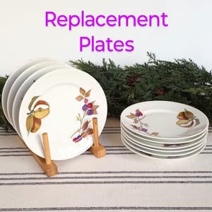 May include: Set of six white ceramic plates with a floral design featuring berries and apples. The plates are stacked on a wooden stand. Replacement Plates.