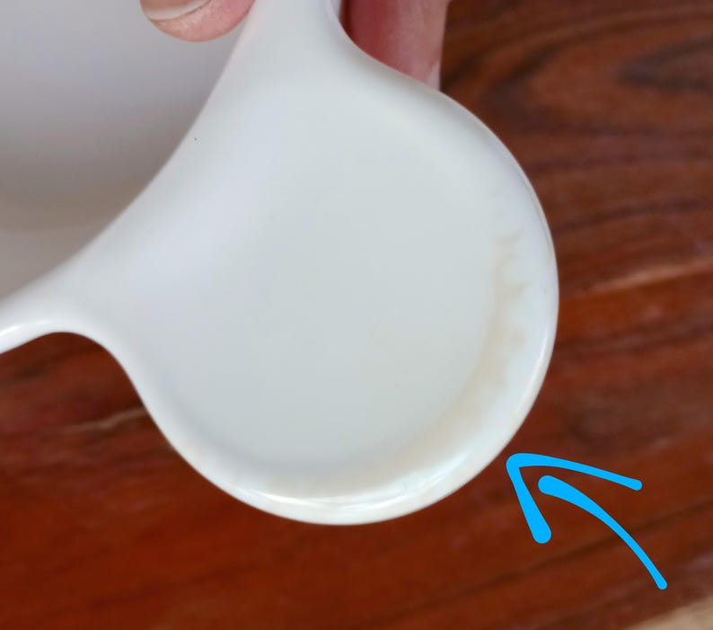 Pode incluir: Uma caneca de cer&acirc;mica branca com uma al&ccedil;a curva. A caneca tem um acabamento liso e brilhante e uma base arredondada. O interior da caneca tamb&eacute;m &eacute; branco. A caneca est&aacute; limpa e parece n&atilde;o utilizada.