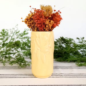 May include: A white ceramic mug with a black handle and the text "But First, Coffee" in a bold, black font. The mug is set against a neutral background, highlighting its simple design.