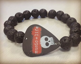 May include: Black lava rock bracelet with a guitar pick charm that says "music=life" and a white skull graphic.