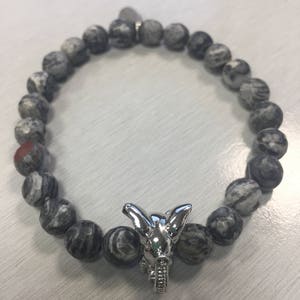 May include: A gray and black stone beaded bracelet with a silver elephant charm.