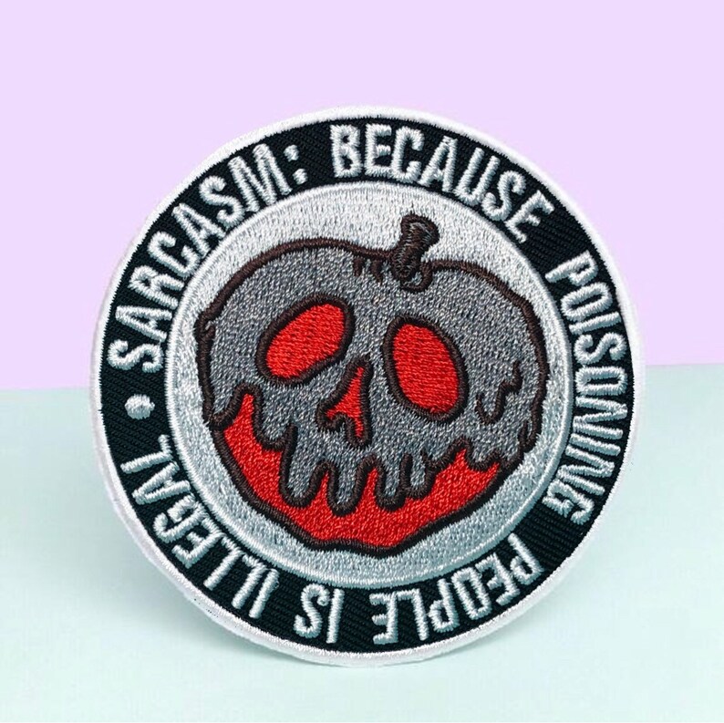 Puede incluir: Parche bordado redondo con un dise&ntilde;o gris, rojo y negro. El parche presenta una manzana con forma de calavera con el texto "Sarcasm: Because People is Illegal Poisoning."