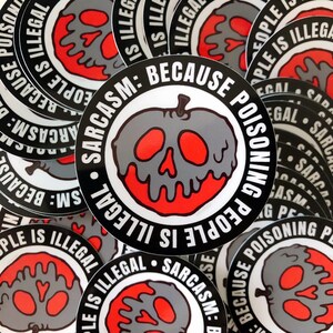 May include: A collection of round stickers with a gray skull-shaped apple design and the text "Sarcasm: Because Poisoning People Is Illegal." The apple has red accents and is surrounded by a black and white border. The stickers are scattered.