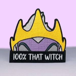 May include: An embroidered iron-on patch featuring a purple and gray cartoon character wearing a yellow crown. The text "100% THAT WITCH" is on a black banner below the character.