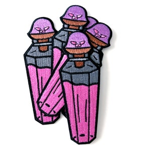May include: Embroidered patches featuring a pink potion bottle design with a purple skull-shaped lid. The bottles have a gray neck and a pink liquid filling. The patches are stacked on a white background.