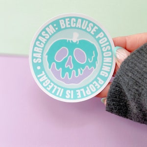May include: A round sticker with a green apple with a skull and dripping purple poison. The sticker says "SARCASM: BECAUSE POISONING PEOPLE IS ILLEGAL"