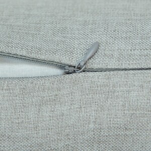 A close-up view of a grey fabric with a zipper visible, suggesting a piece of clothing or textile.