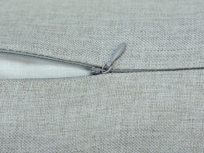 A close-up view of a grey fabric with a zipper visible, suggesting a piece of clothing or textile.