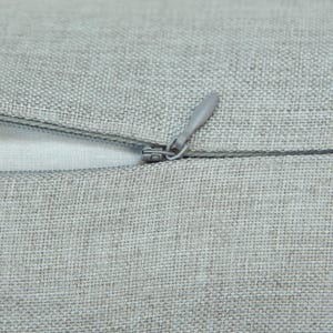 A close-up view of a grey fabric with a zipper visible, suggesting a piece of clothing or textile.