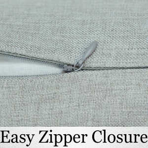 May include: Close-up of a gray zipper closure on a pillow cover. The zipper is easy to use and allows for easy removal and insertion of the pillow insert.