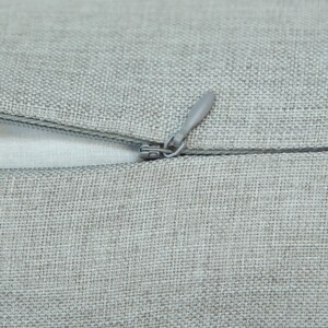 A close-up view of a grey fabric with a zipper visible, suggesting a piece of clothing or textile.