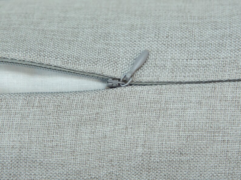 A close-up view of a grey fabric with a zipper visible, suggesting a piece of clothing or textile.