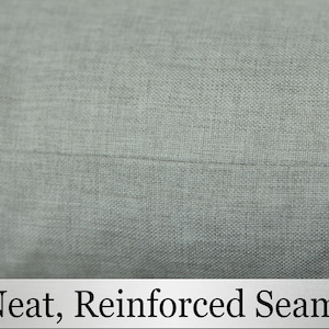 May include: Close-up of a light gray fabric with a straight seam. The text "Neat, Reinforced Seams" is printed below the fabric.