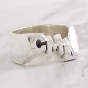 May include: A silver ring with the letters "CMJ" engraved on it.