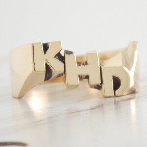 May include: A gold ring with the letters "KHD" engraved on it.