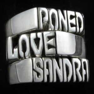 May include: A silver ring with the words "Loved", "Poned", and "Sandra" engraved on it.