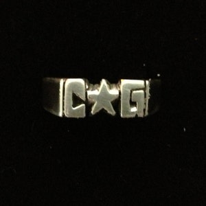 May include: A silver ring with the letters "C*G" engraved on it.