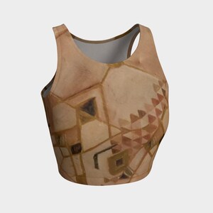 May include: A sleeveless crop top featuring a beige and tan color palette with a geometric pattern of interconnected shapes, lines, and small triangles. The garment has a round neckline and a cropped hemline, showcasing a repeating abstract design.