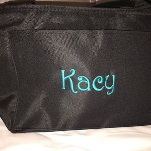 May include: Black insulated tote bag with a teal embroidered name "Kacy" on the front.