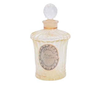 Pu&ograve; includere: Un flacone di profumo vintage con un corpo in vetro trasparente strutturato e un tappo decorativo trasparente. La bottiglia ha un'etichetta con testo e un collo color oro. Il colore generale &egrave; un bianco crema morbido.