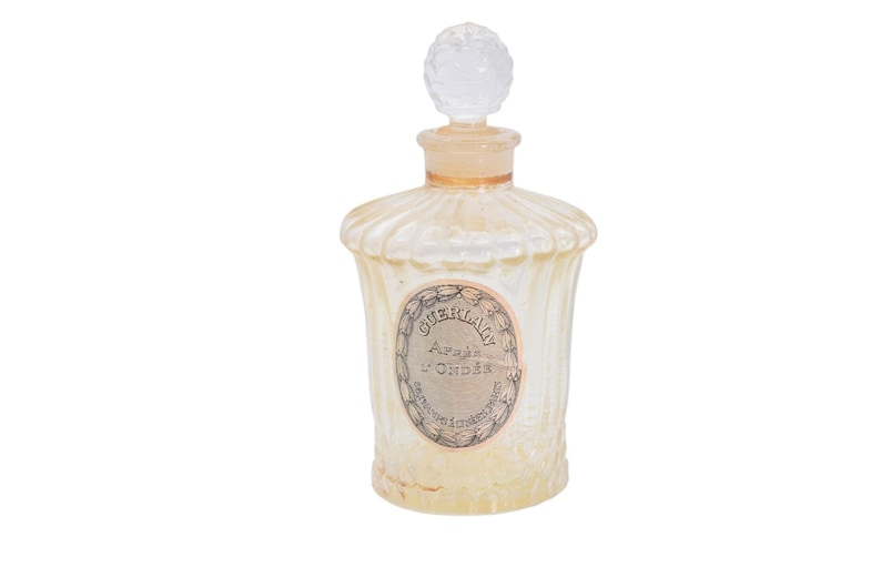 Pu&ograve; includere: Un flacone di profumo vintage con un corpo in vetro trasparente strutturato e un tappo decorativo trasparente. La bottiglia ha un'etichetta con testo e un collo color oro. Il colore generale &egrave; un bianco crema morbido.