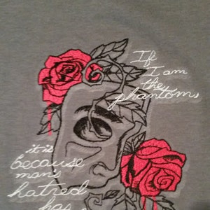 May include: Gray t-shirt with embroidered roses and a skull with the text "If I am the phantoms it is because man's hatred has made me so."