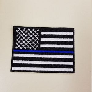 May include: Black and white American flag patch with a thin blue line across the middle.