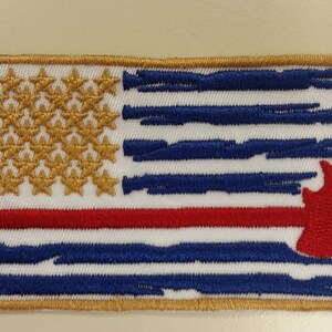May include: An embroidered patch featuring a distressed American flag with a red line across the middle and a red firefighter axe in the bottom right corner.
