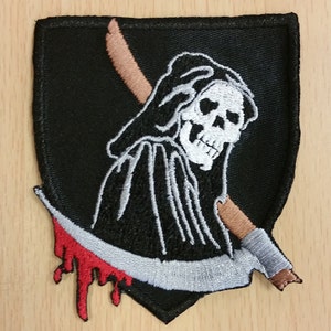 Peut inclure: Patch brodé noir et blanc du Grim Reaper tenant une faux avec une goutte de sang rouge. Le patch est en forme de bouclier.