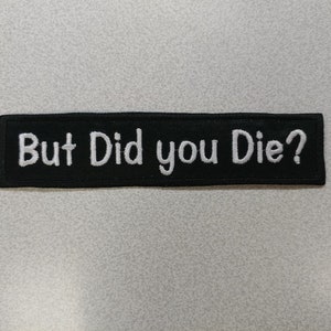May include: Black and white embroidered patch with the text "But Did you Die?"