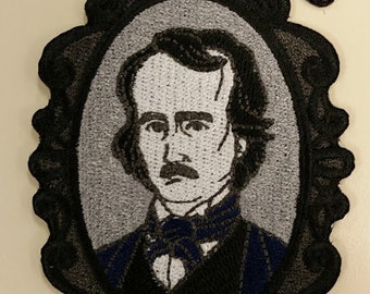 Puede incluir: Parche bordado con un retrato de Edgar Allan Poe en un marco negro ornamentado, con un cuervo negro encima. El retrato es en tonos grises y negros, con un acento azul en la ropa. Tema gótico.