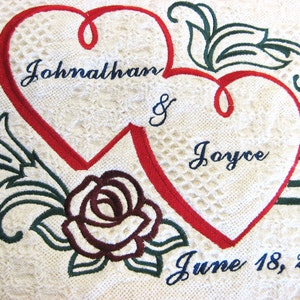 May include: Embroidered white towel with two red hearts, a rose, and the text "Johnathan & Joyce June 18, 2011".