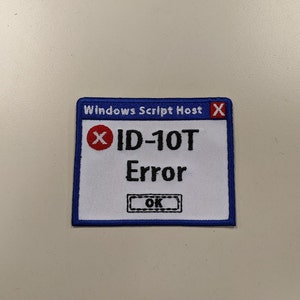Peut inclure: Un patch brodé blanc et bleu avec une bordure bleue. Le patch est en forme de boîte de message d'erreur Windows. Le texte sur le patch indique "Windows Script Host" dans la barre de titre, "ID-10T Error" dans la boîte de message et "OK" sur un bouton.