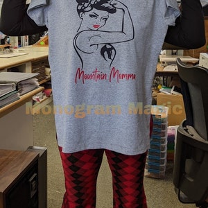 May include: Gray t-shirt with a black and white illustration of a woman with a red bandana and the text "Mountain Momma" in red.