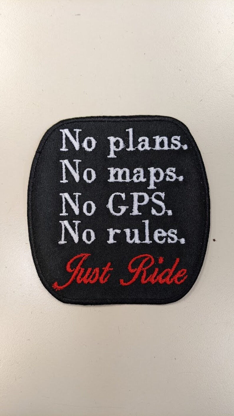 May include: Black embroidered patch with white text that reads "No plans. No maps. No GPS. No rules. Just Ride" in red.