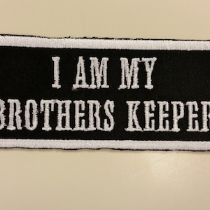 May include: Black embroidered patch with white stitching that reads "I AM MY BROTHERS KEEPER".