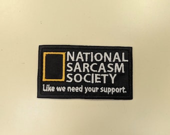 May include: Black rectangular patch with the text "NATIONAL SARCASM SOCIETY" in white letters. The patch features a yellow square with a black interior. Below the text is the phrase "Like we need your support."