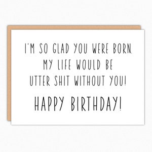 May include: A white greeting card with a brown border. The black text reads: "I'M SO GLAD YOU WERE BORN. MY LIFE WOULD BE UTTER SHIT WITHOUT YOU! HAPPY BIRTHDAY!"