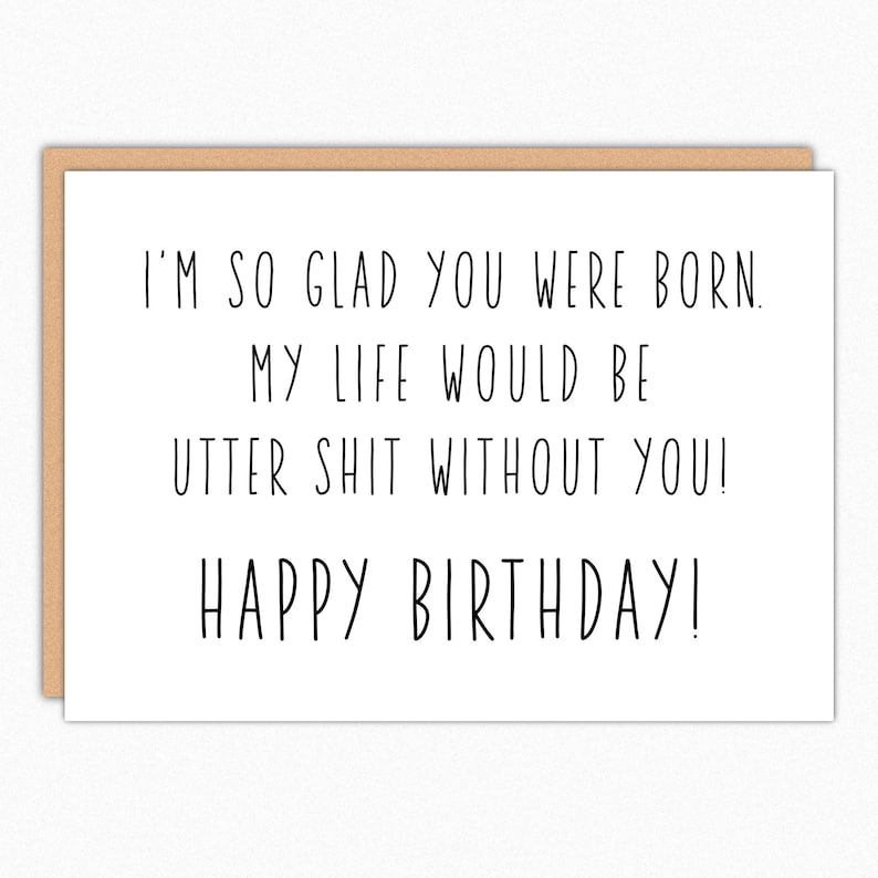 Op de afbeelding: Een witte wenskaart met een bruine rand. De zwarte tekst luidt: "I'M SO GLAD YOU WERE BORN. MY LIFE WOULD BE UTTER SHIT WITHOUT YOU! HAPPY BIRTHDAY!"